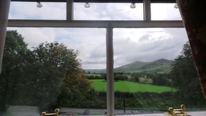 A window with a view of a green landscape and hills. - Rambler Inn (Hope Valley)