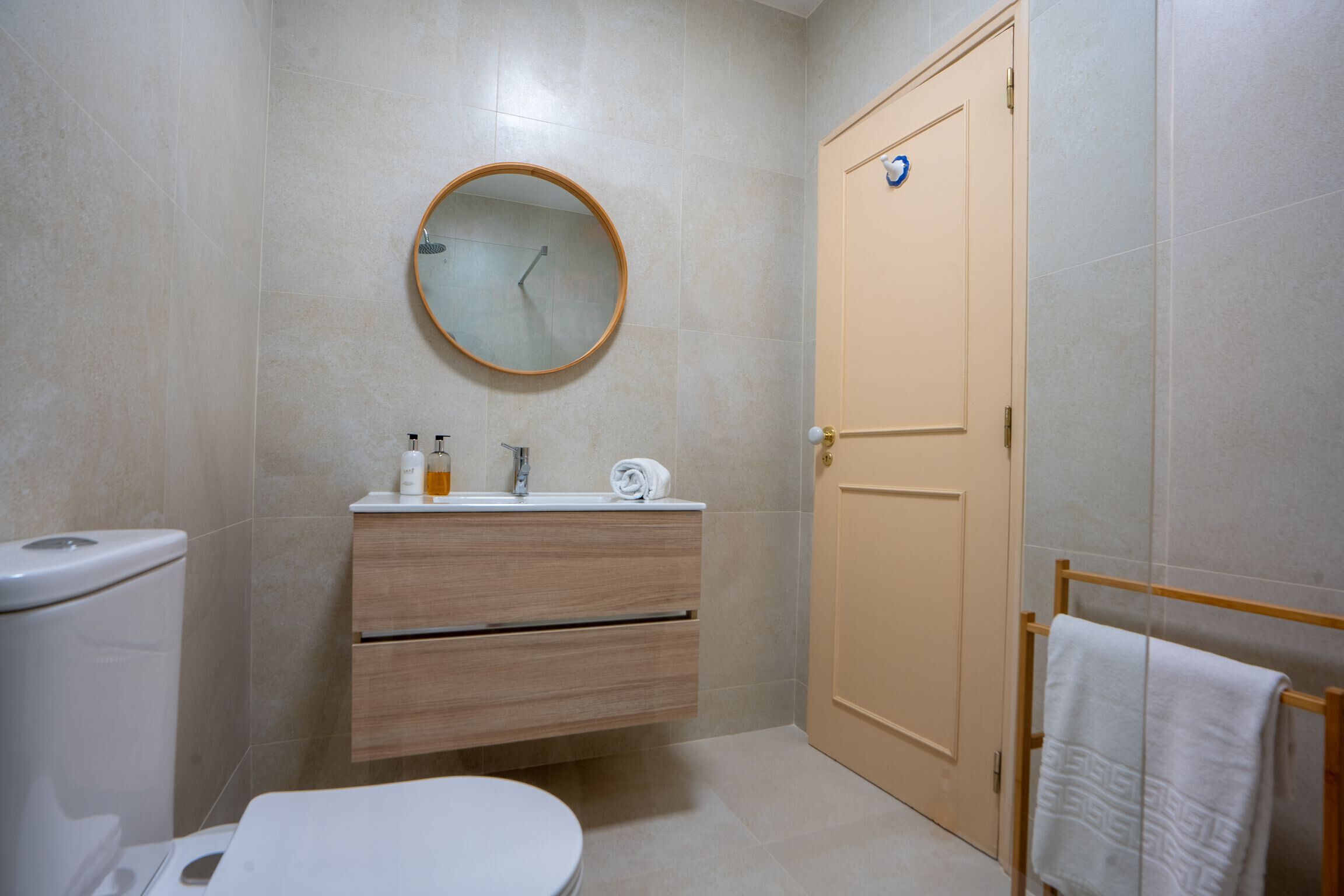 A bathroom with a toilet, sink, mirror, and towel rack.