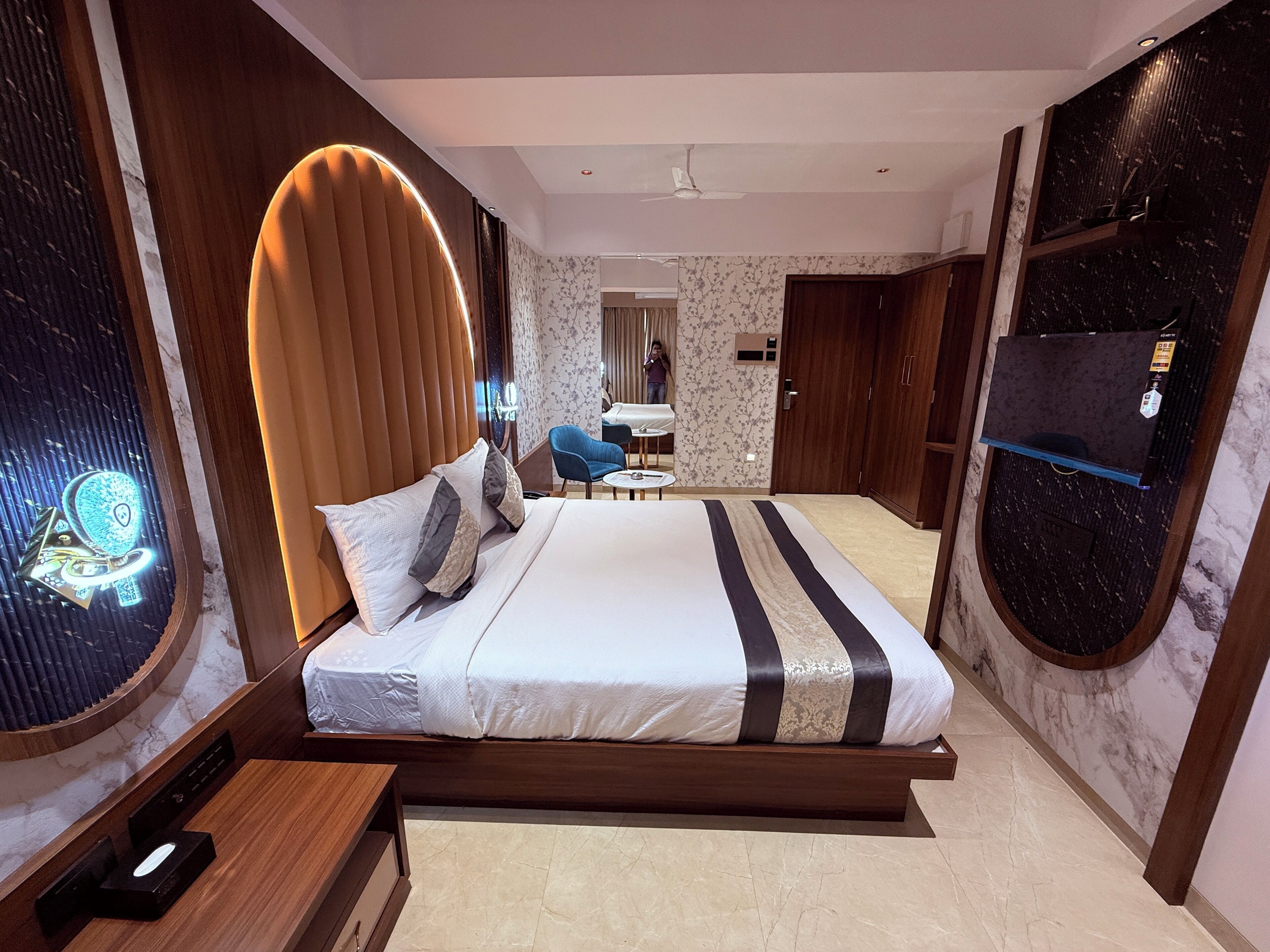 A modern hotel room with a large bed, a desk, a chair, and a TV.