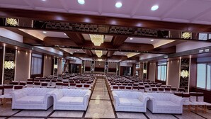Un amplio salón con filas de sofás y sillones blancos, suelo de mármol pulido y un techo alto con iluminación empotrada.