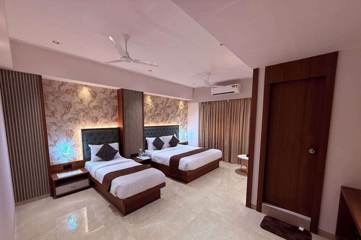 A hotel room with two beds, a wooden door, a ceiling fan, and an air conditioning unit.