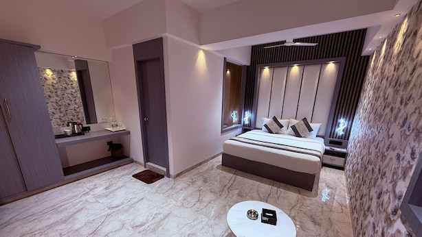 Un dormitorio moderno con una cama grande, una mesita de noche, una pequeña mesa redonda y un baño con espejo y lavamanos.