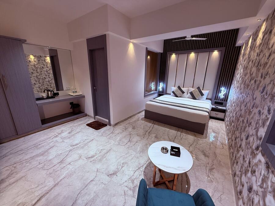 A modern bedroom with a large bed, a bedside table, a small round table, and a bathroom with a mirror and sink.