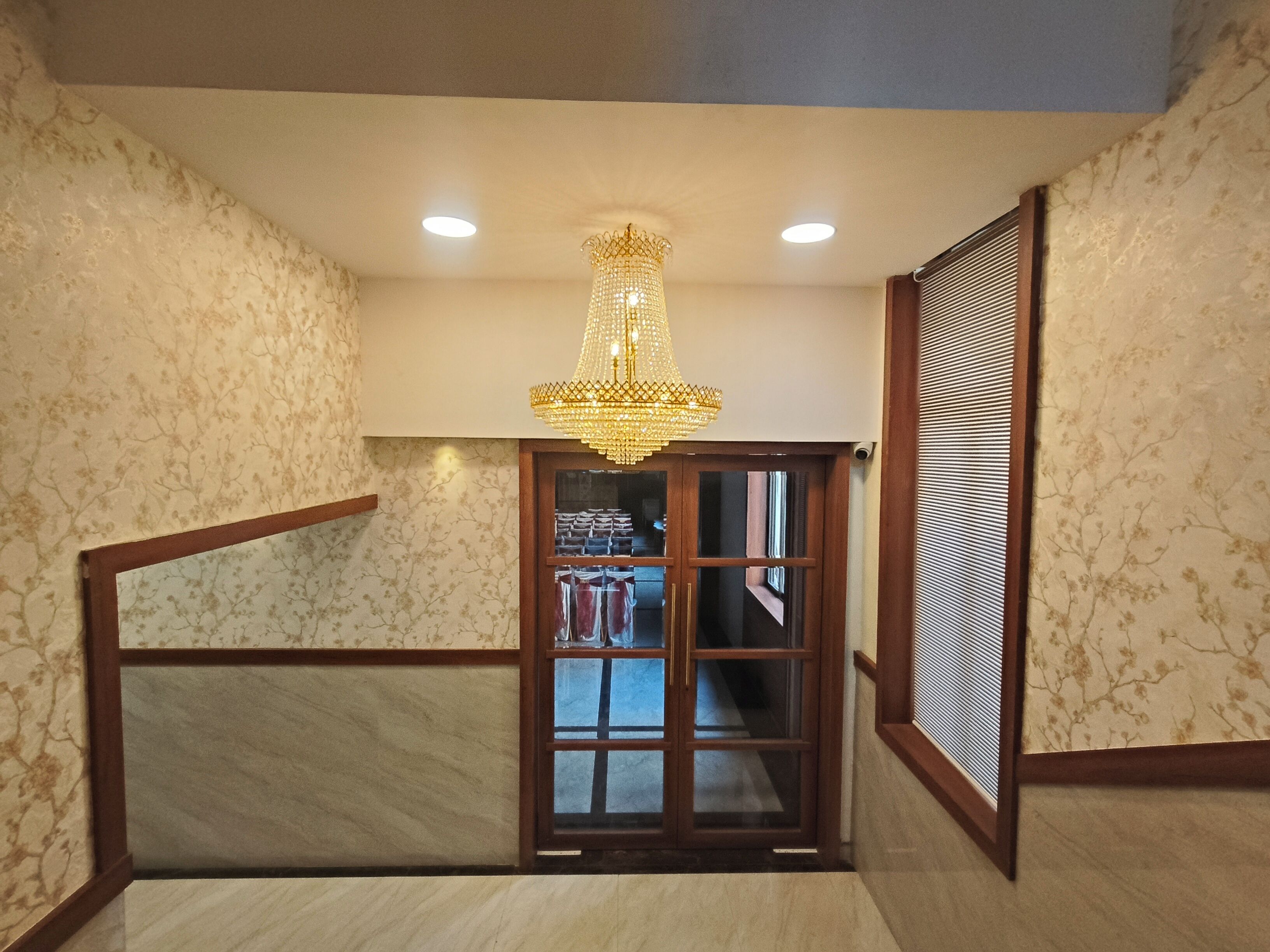Una habitación con candelabro, puerta de madera y papel tapiz estampado.