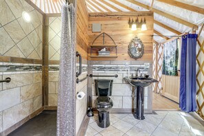 Un baño con techo de madera, inodoro, lavabo y cortina de ducha.
