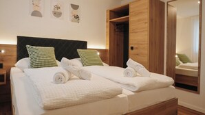 A double bed with a wooden frame, two pillows, and neatly folded towels. - Be Grand Apartments Rust (Rust)