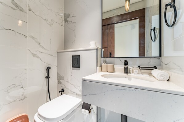Une salle de bain moderne avec un lavabo en marbre, des toilettes et une douche.
