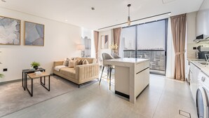 A modern living room with a sofa, a coffee table, and a dining area with a kitchen in the background. - Mins from City Walk, Downtown Dubai and Jumeirah Beach, Easy Access to Metro Stations (Dubai)