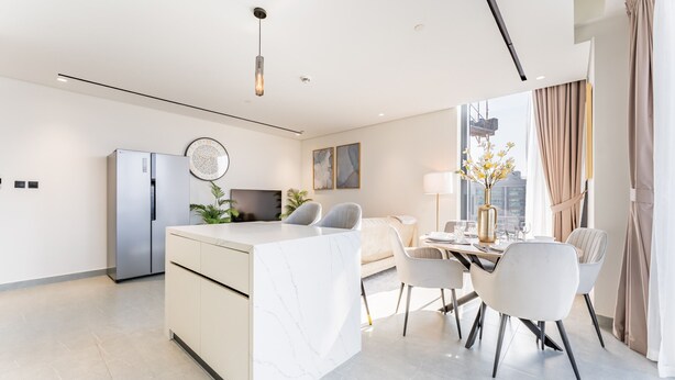 A modern kitchen with a marble island, stainless steel appliances, and a dining area with a table and chairs. - Mins from City Walk, Downtown Dubai and Jumeirah Beach, Easy Access to Metro Stations (Dubai)