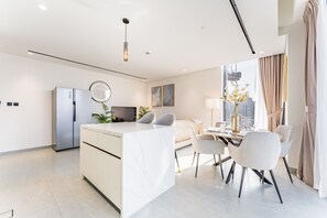 Une cuisine moderne dotée d’un îlot en marbre, d’appareils électroménagers en acier inoxydable et d’un coin repas avec une table et des chaises.