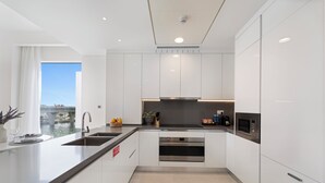 A modern kitchen with white cabinetry, stainless steel appliances, and a large island. - 2BR M Canal Front B3 Waterfront Views (Dubai)