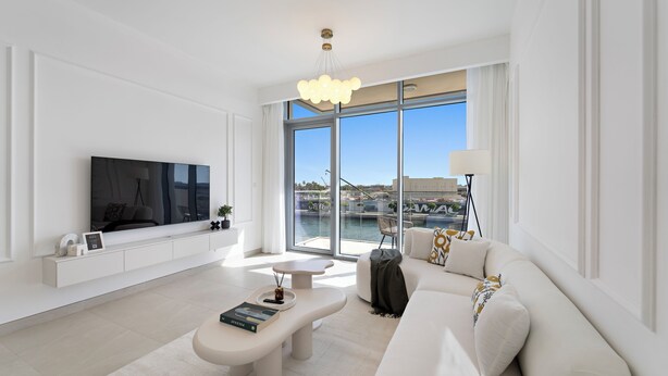 A modern living room with a large flat-screen TV, a white sofa, a coffee table, and a large window offering a view of the city. - 2BR M Canal Front B3 Waterfront Views (Dubai)