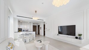 A modern living room with a sofa, a coffee table, and a TV mounted on the wall. - 2BR M Canal Front B3 Waterfront Views (Dubai)