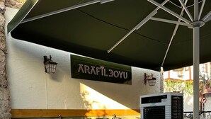 A restaurant with outdoor seating, tables set with plates and cutlery, and a sign reading "TRAFILLOYU". - Hotel Zurich Oldtown (Antalya)