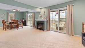 A spacious living room with a fireplace, a dining area with wooden furniture, and large sliding glass doors leading to a deck.