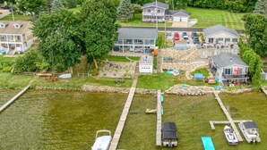 An aerial view of a lakeside property with a dock, boats, and houses.