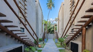 A narrow pathway flanked by buildings with wooden staircases and palm trees. - House w/ Pool 140m From the Beach Clb0002 (São Miguel dos Milagres)