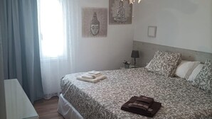 A bedroom with a bed, a bedside table, a lamp, and a window with curtains. - The Balcony of the 4 Moons - Apartment 631 (Costa Teguise)