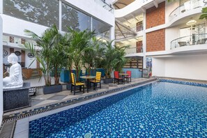 An indoor swimming pool with tiled blue floor, surrounded by potted plants and outdoor seating. - Echor Kia - A Boutique Hotel Anjuna Goa (Anjuna)