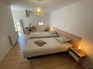 Un dormitorio con dos camas, un escritorio, una silla y una lámpara colgante.