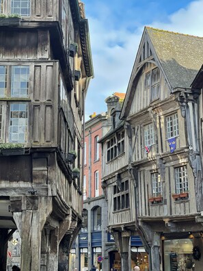 Una calle estrecha flanqueada por edificios tradicionales con entramado de madera, algunos con escaparates y rótulos.