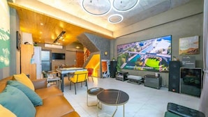 A modern living room with a large flat-screen TV, a sofa, a dining area with chairs, and a kitchen in the background. - Xiuhu Lodge (Jiaoxi)