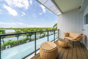 A balcony with a view of a lake and greenery, a wicker sofa, and a round wicker stool. - Xiuhu Lodge (Jiaoxi)