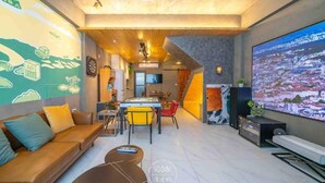 A modern living room with a sofa, coffee table, and a large TV screen displaying a cityscape. - Xiuhu Lodge (Jiaoxi)