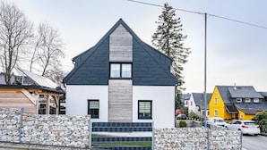 Ein modernes, zweistöckiges Haus mit Steinmauer und schmiedeeisernem Tor.