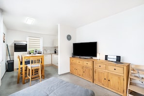 A modern kitchen with a dining area, a flat-screen TV, and a wooden cabinet.