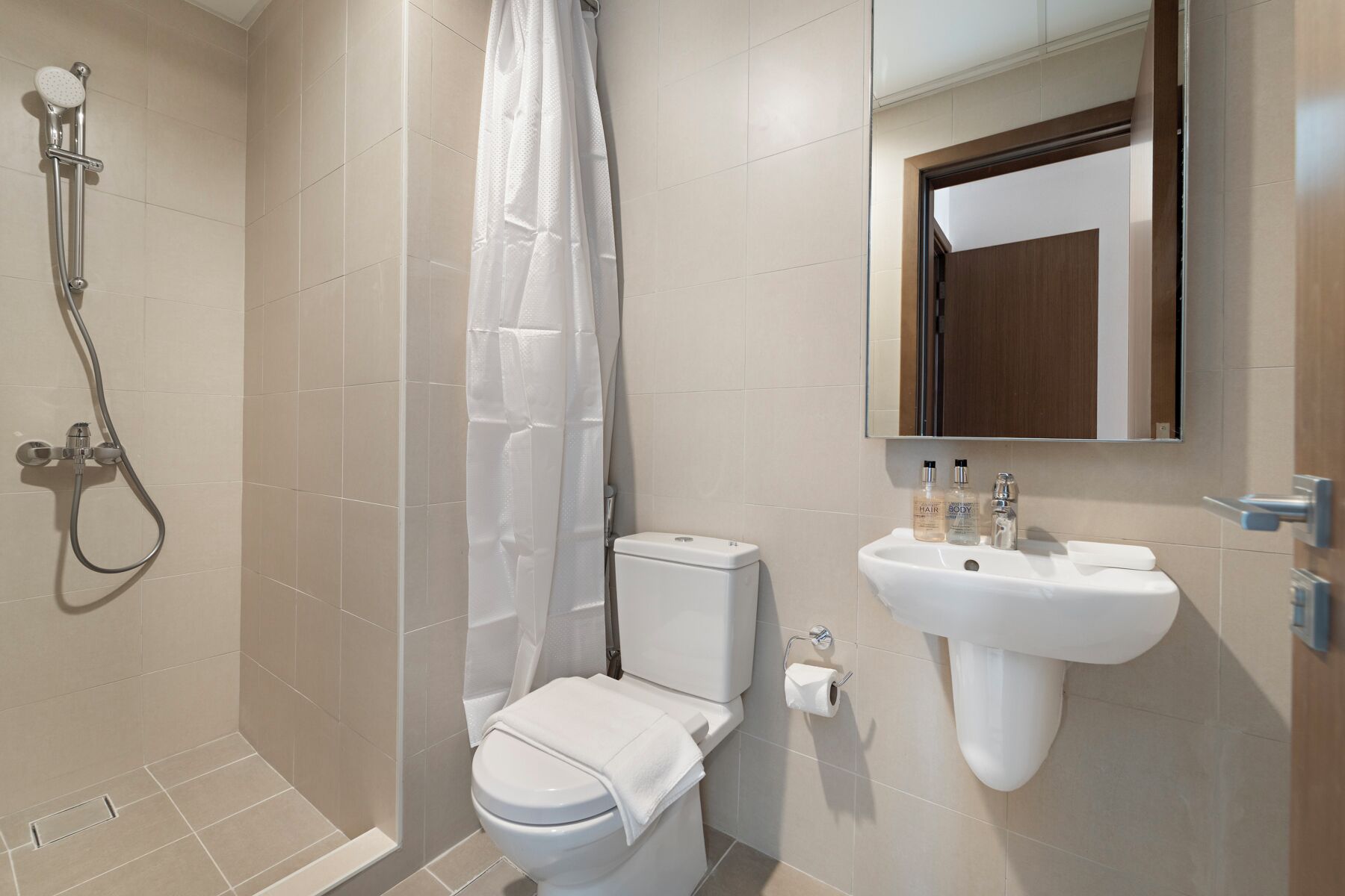Ein modernes Badezimmer mit Dusche, Toilette, Waschbecken und Spiegel.