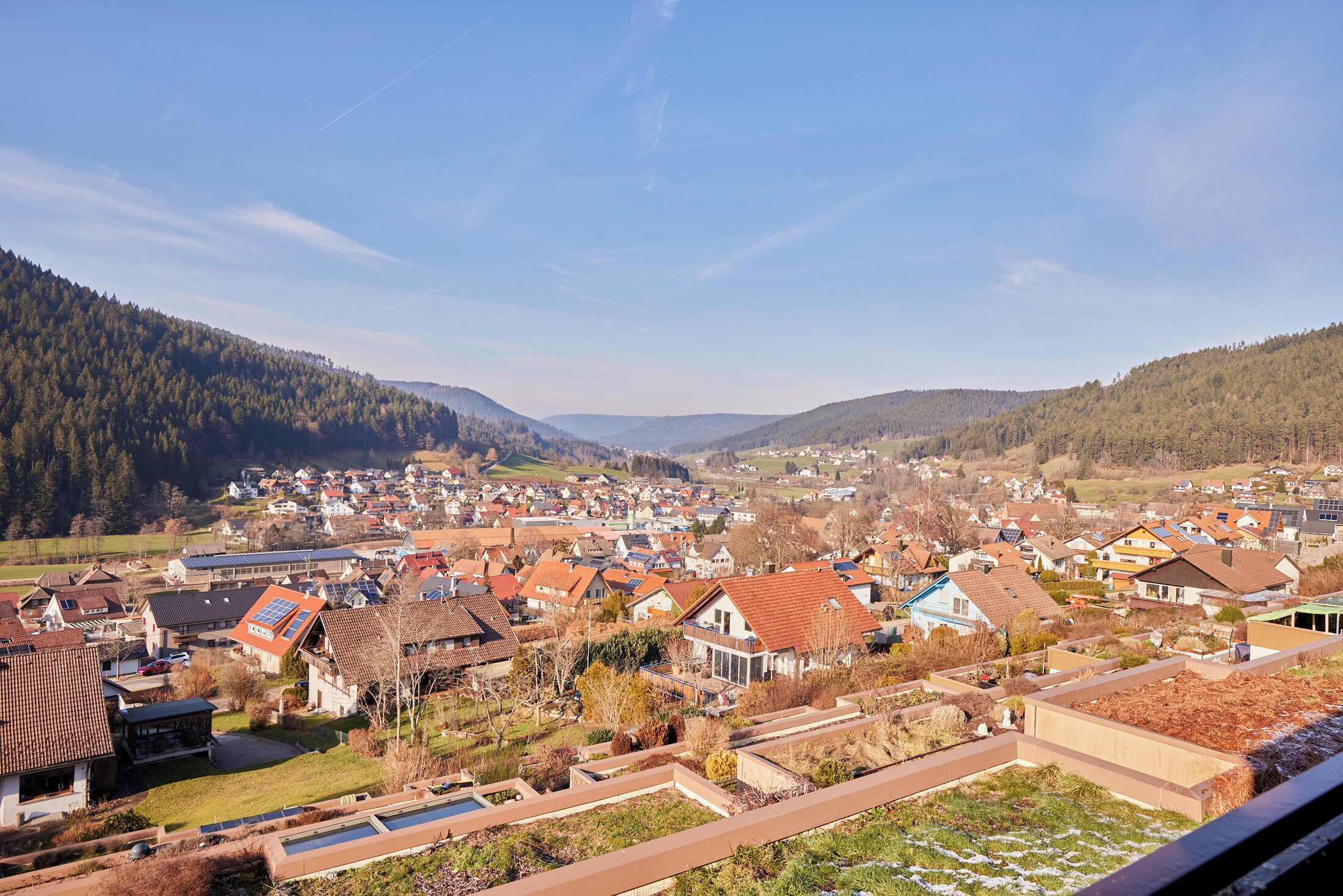 A residential area with houses, a swimming pool, and a hilly landscape in the background.