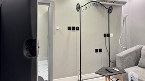 Una habitación moderna con un sofá gris, una mesita con un mando a distancia, un equipo de aire acondicionado y un calefactor portátil.