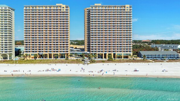 Un hôtel situé en bord de mer, composé de plusieurs immeubles de grande hauteur, avec une plage de sable fin et une eau turquoise cristalline.