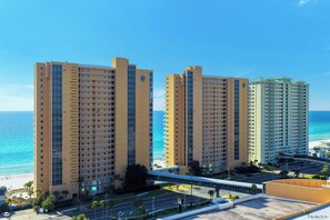 Un hôtel de grande hauteur, avec de nombreux étages, une vue sur la plage et un parking.