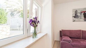 A room with a window, a purple sofa, and a painting on the wall. - Balen House (Novalja)