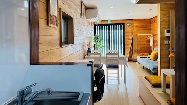 Ein modernes Hotelzimmer mit Küchenzeile, einem Esstisch und einer gemütlichen Sitzecke mit Sofa und Bett.
