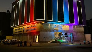 Een hotel met een moderne gevel, grote ramen en een bord met de tekst Alawaleen Hayah Hotel.
