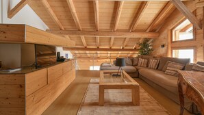 Een houten interieur met een bank, een bijzettafeltje en een televisie op een houten kast.