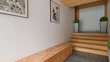 A staircase with wooden steps leading to a door, a wooden bench, and two potted plants.