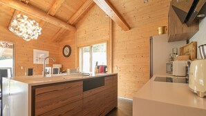 Een moderne keuken met houten wanden, een groot eiland en een hanglamp.