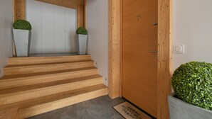 Een houten trap die naar een deur leidt, met twee plantenbakken aan weerszijden.