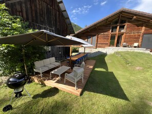 Une terrasse avec mobilier d’extérieur, un barbecue et une plateforme en bois.