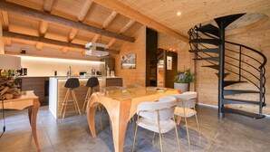 Une cuisine moderne avec des poutres en bois, un îlot central, des tabourets de bar et un escalier en colimaçon.