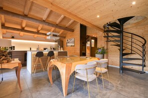 Eine moderne Küche mit Holzbalken, einer zentralen Kochinsel, Barhocker und einer Wendeltreppe.