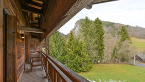 Un balcon en bois offrant une vue sur une colline boisée.