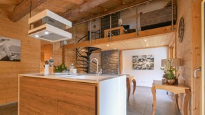 Une cuisine moderne dotée d’un îlot central, de meubles en bois, d’une cuisinière intégrée et d’un mur d’accent en pierre.