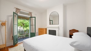 A bedroom with a bed, a dresser, a mirror, and a door leading to an outdoor area. - Stylish 2-bed House With Private Courtyard (Sydney)