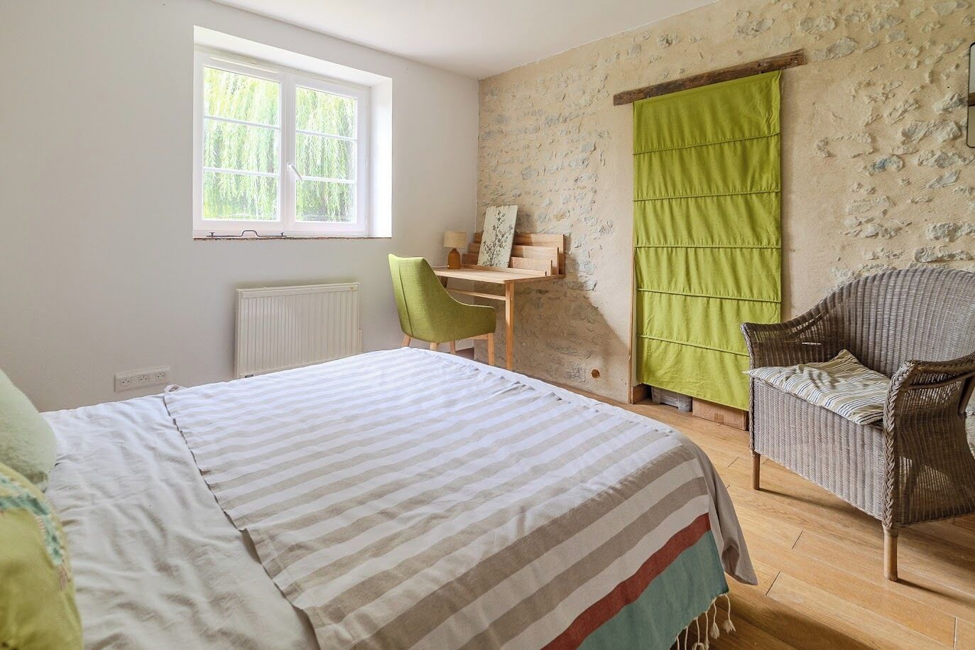 A bedroom with a bed, a desk, a chair, and a window.