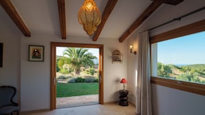 A room with a large window, a door leading outside, a lamp, and a chair. - THE HIDEOUT Exclusive residence surrounded by nature, near Porto Rotondo (Sardegna)